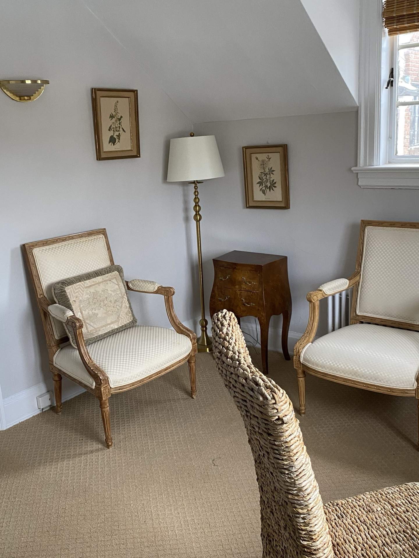 Room corner with botanical prints, brass lamp, and upholstered chair at The Phillips Mansion
